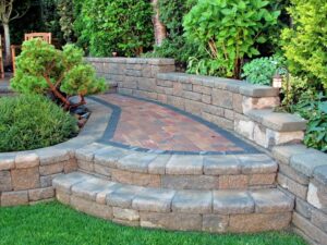 Curved stone patio with steps, retaining walls, and lush garden plants in Ogden, UT